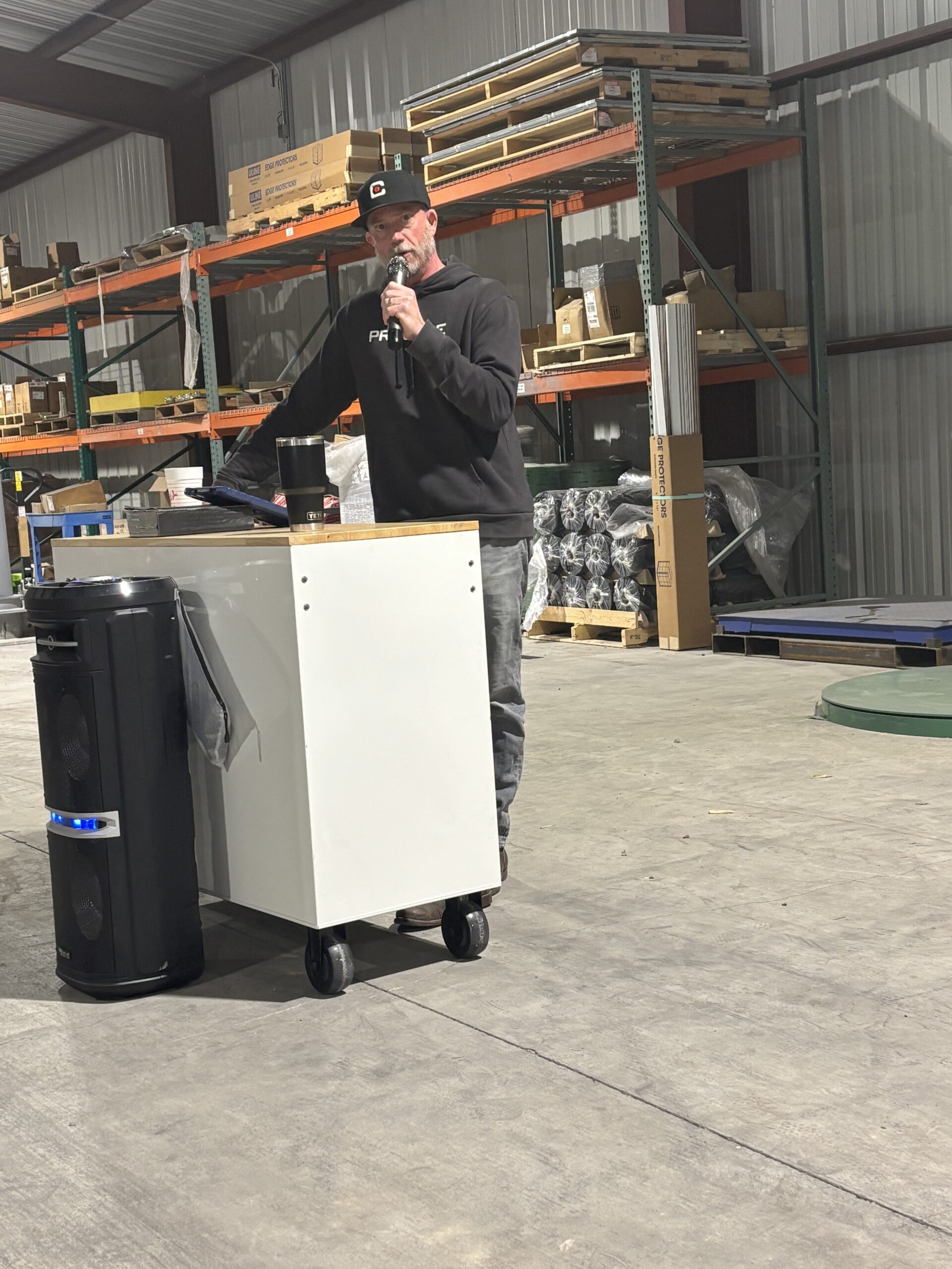 Matt Kelly speaking into microphone at Gibraltar fabrication shop during witness testimony